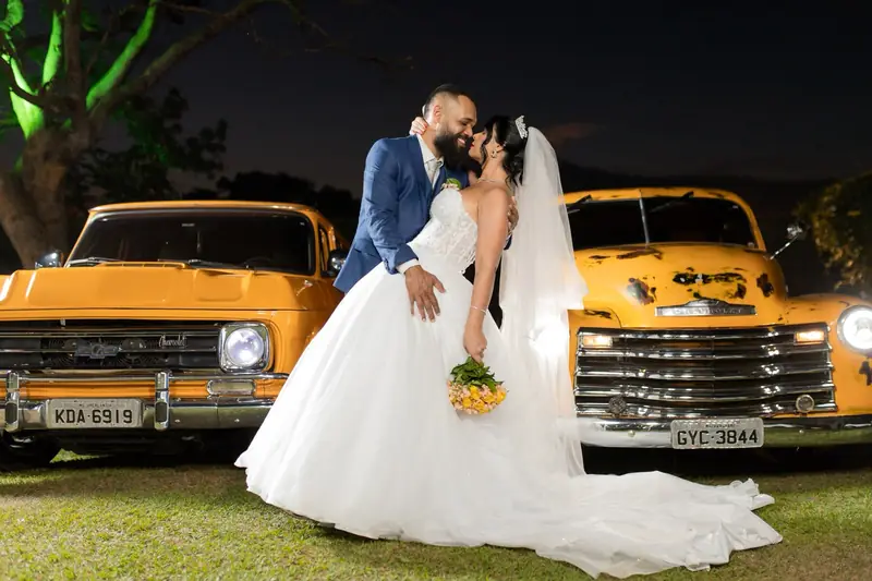 O beijo dos noivos com os dois carros de cenário